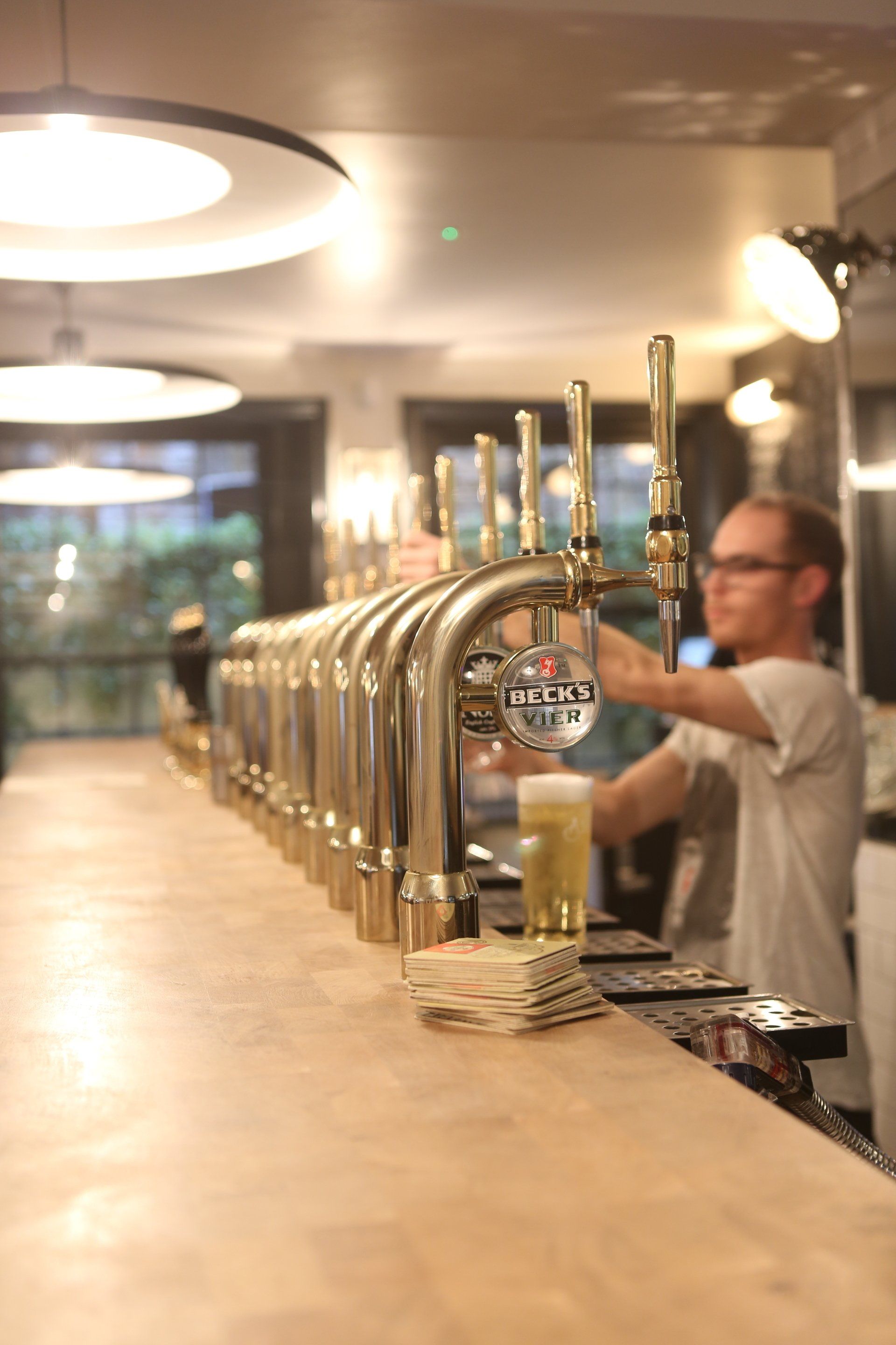 A man is pouring a beer from a tap that has the letter l on it