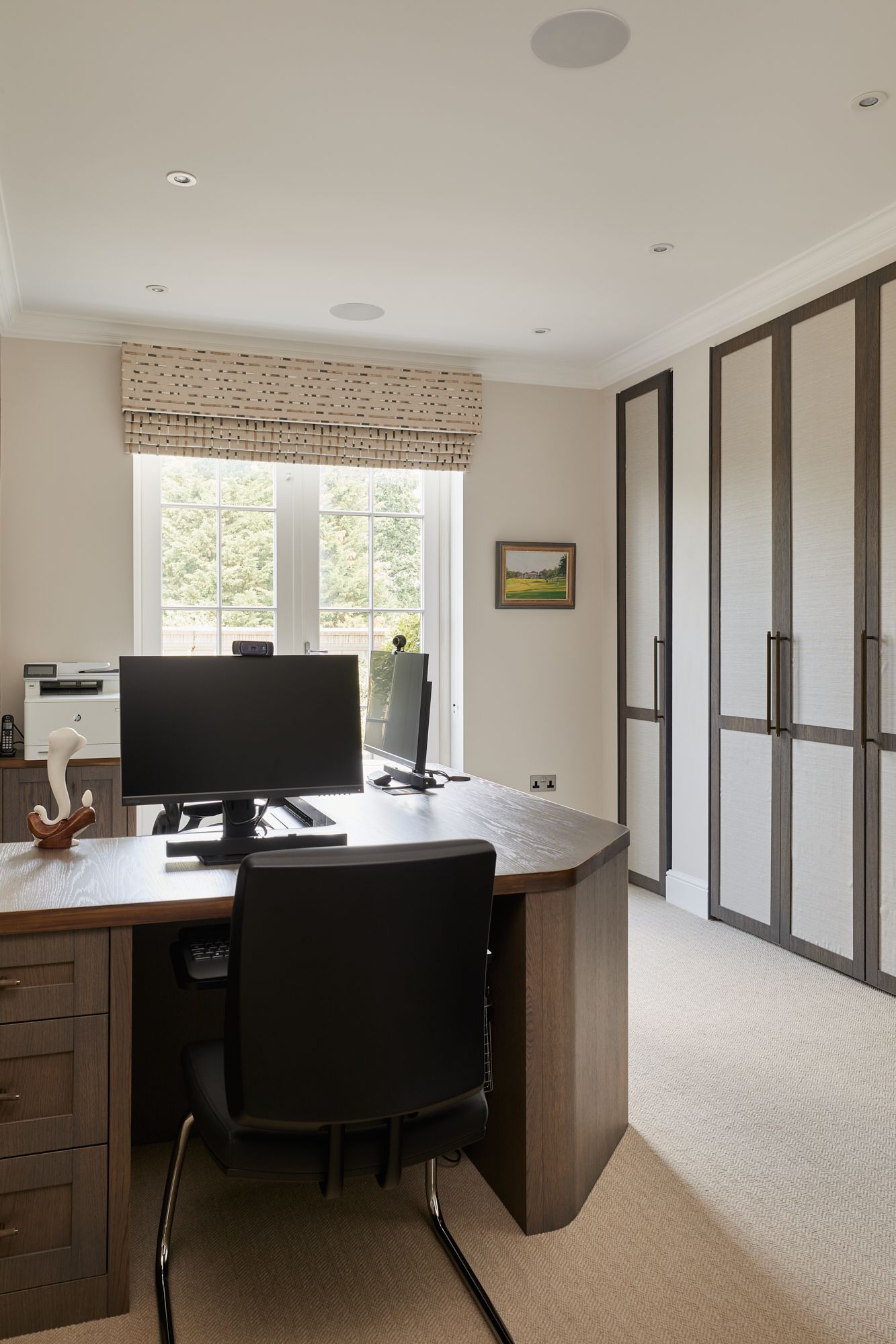 A home office with two computer monitors and a printer