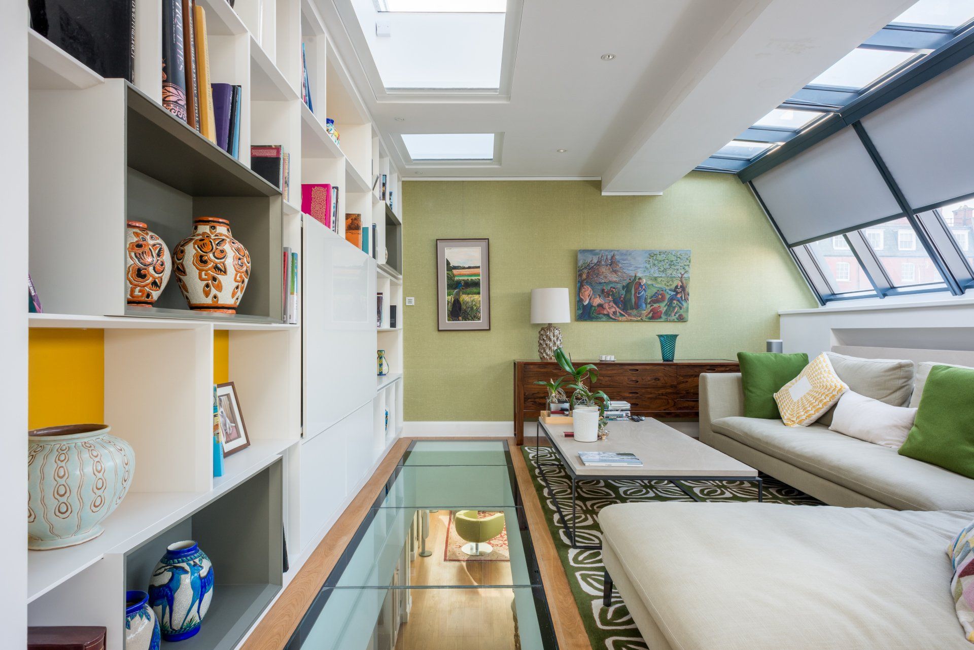 A living room with a white couch and green pillows