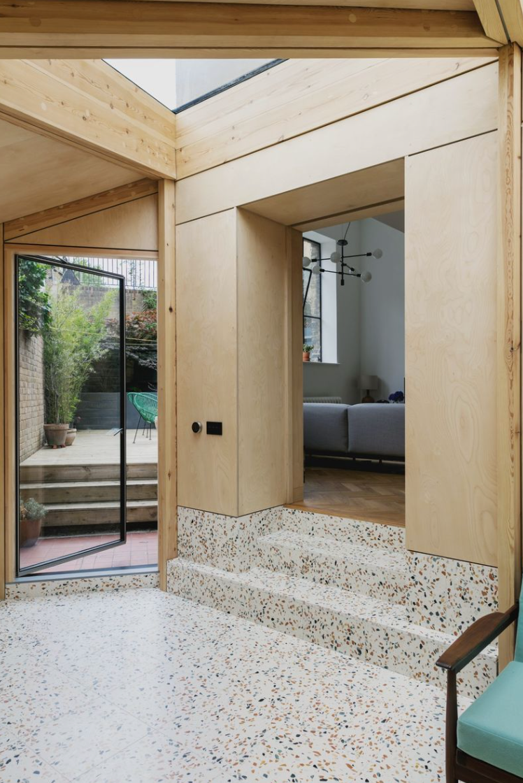 A room with a chair and stairs leading to a living room