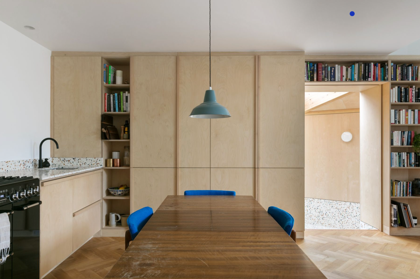 A kitchen with a wooden table and blue chairs