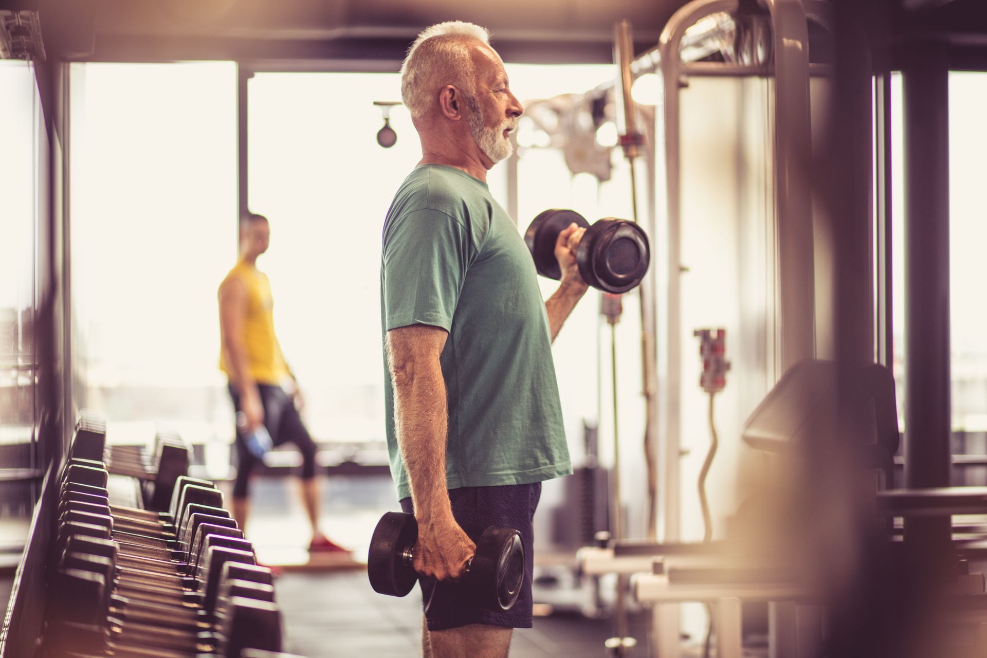 Older adult lifting dumbbells in a gym.