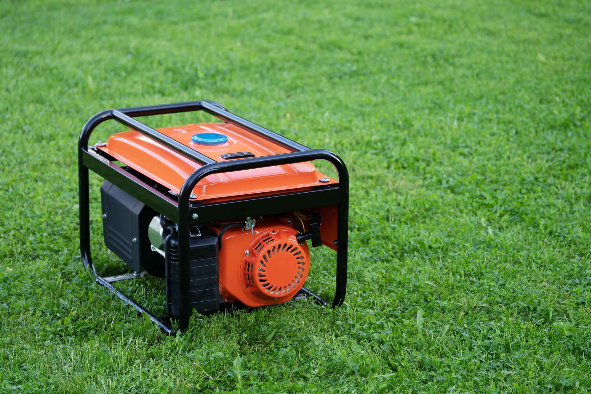 A small orange generator is sitting on top of a lush green field.