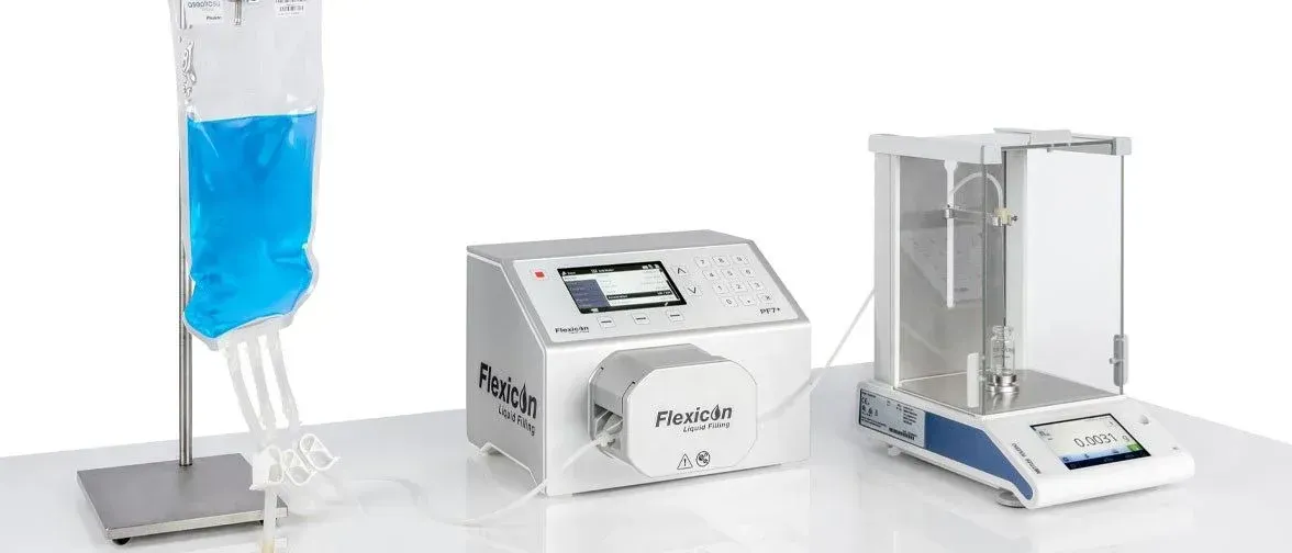 Medical equipment setup: IV bag, pump, and analytical balance on a table.