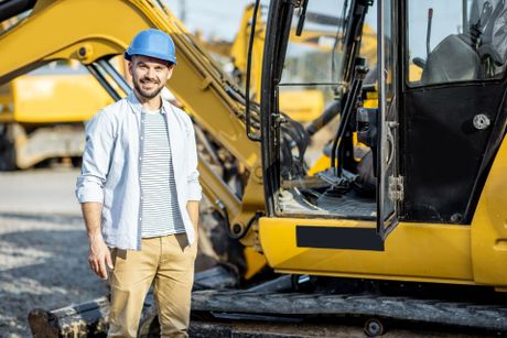 Builder standing near the excavator on the open ground