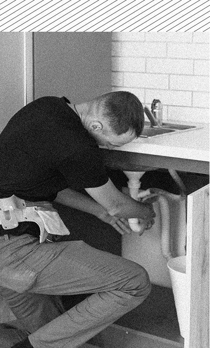 A man is fixing a sink in a black and white photo.