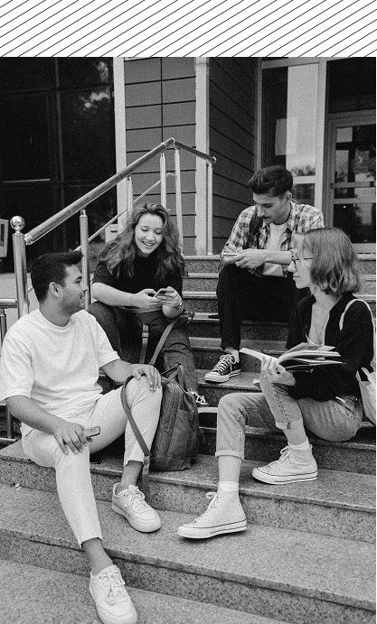 A group of young people are sitting on the steps of a building.