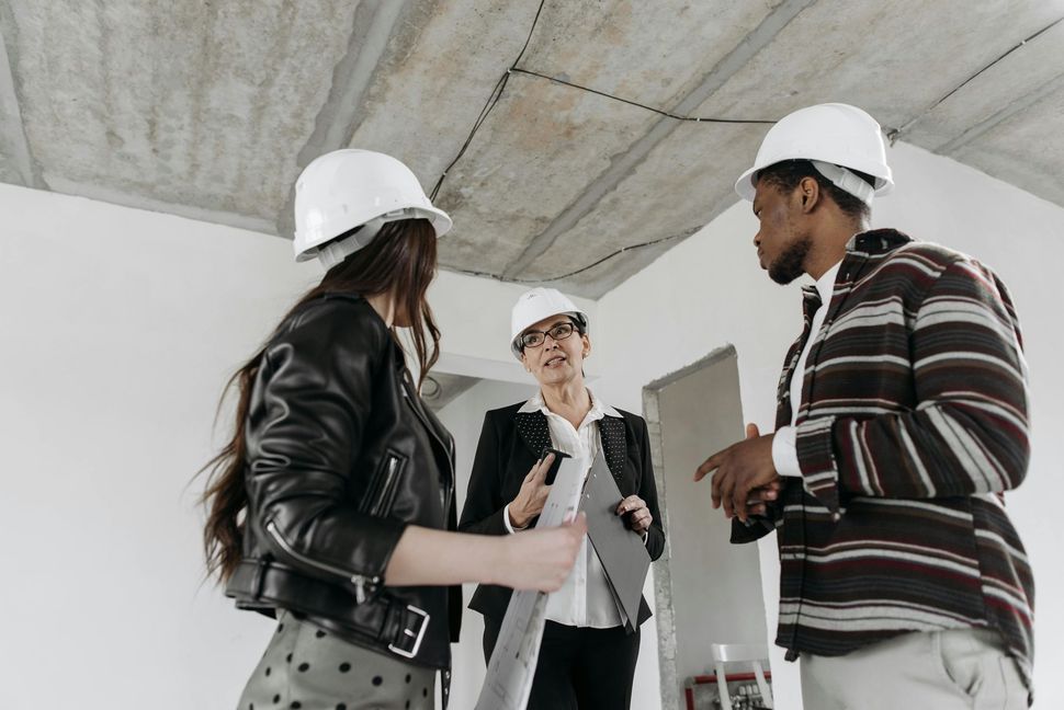 A group of people wearing hard hats are standing in a room.