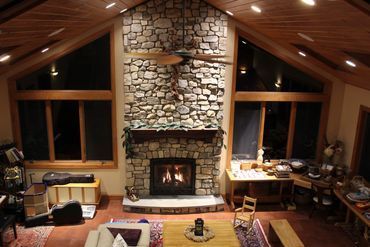 A living room with a stone fireplace and a ceiling fan