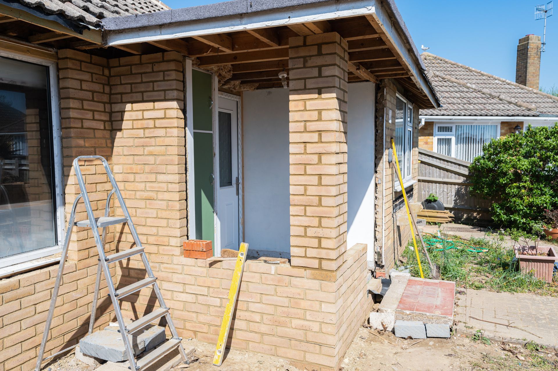 A brick house is being remodeled with a porch and stairs.