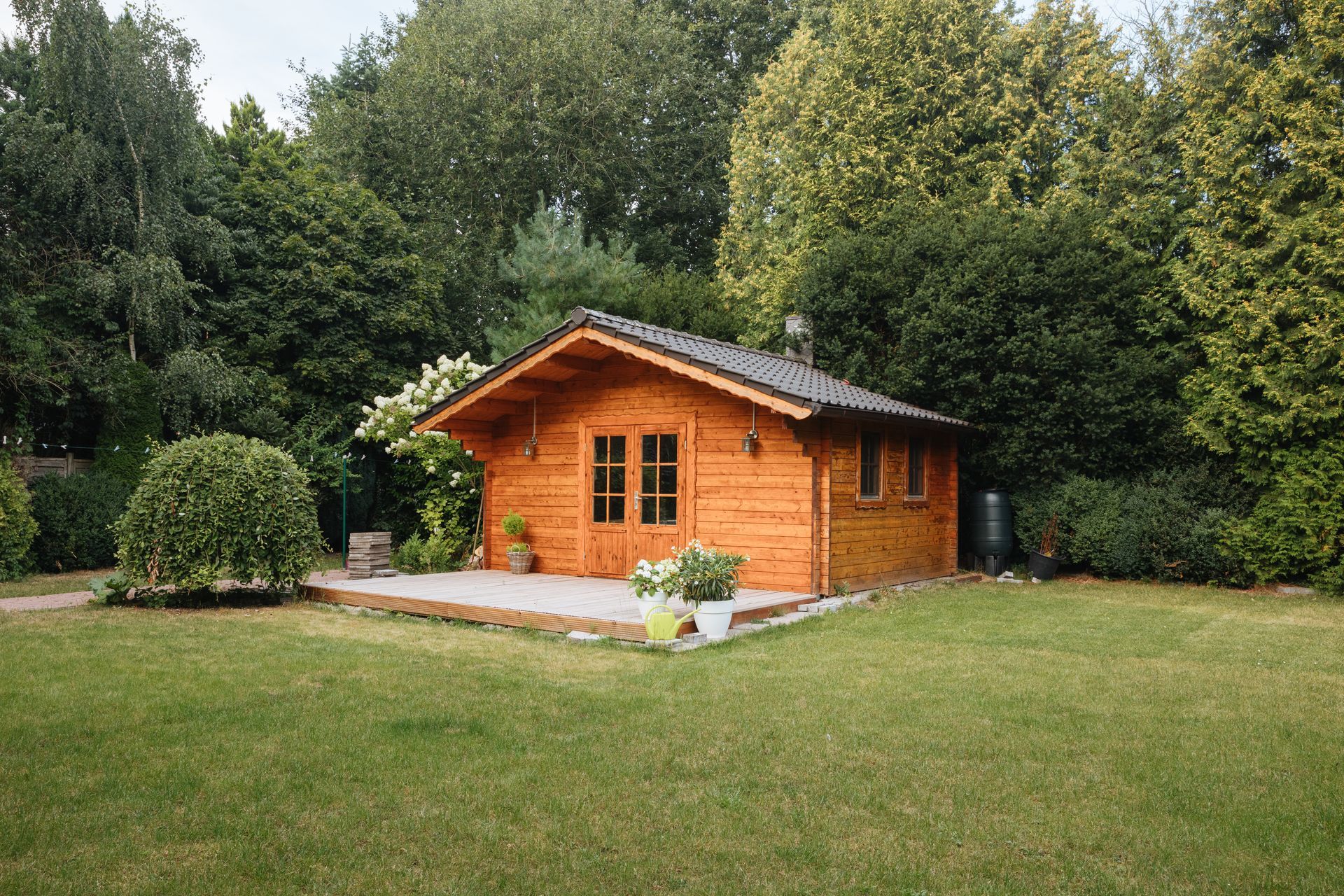 A small wooden house is sitting in the middle of a lush green field.