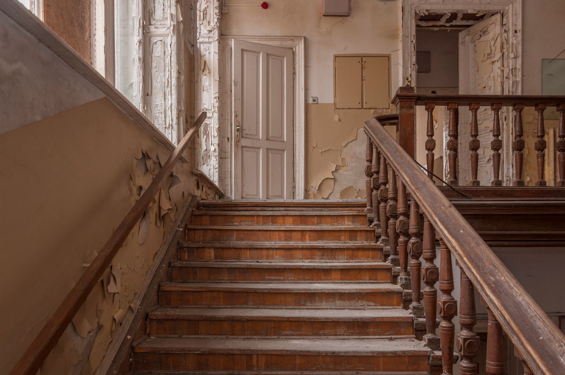 An old wooden staircase with a wooden railing in an abandoned building.