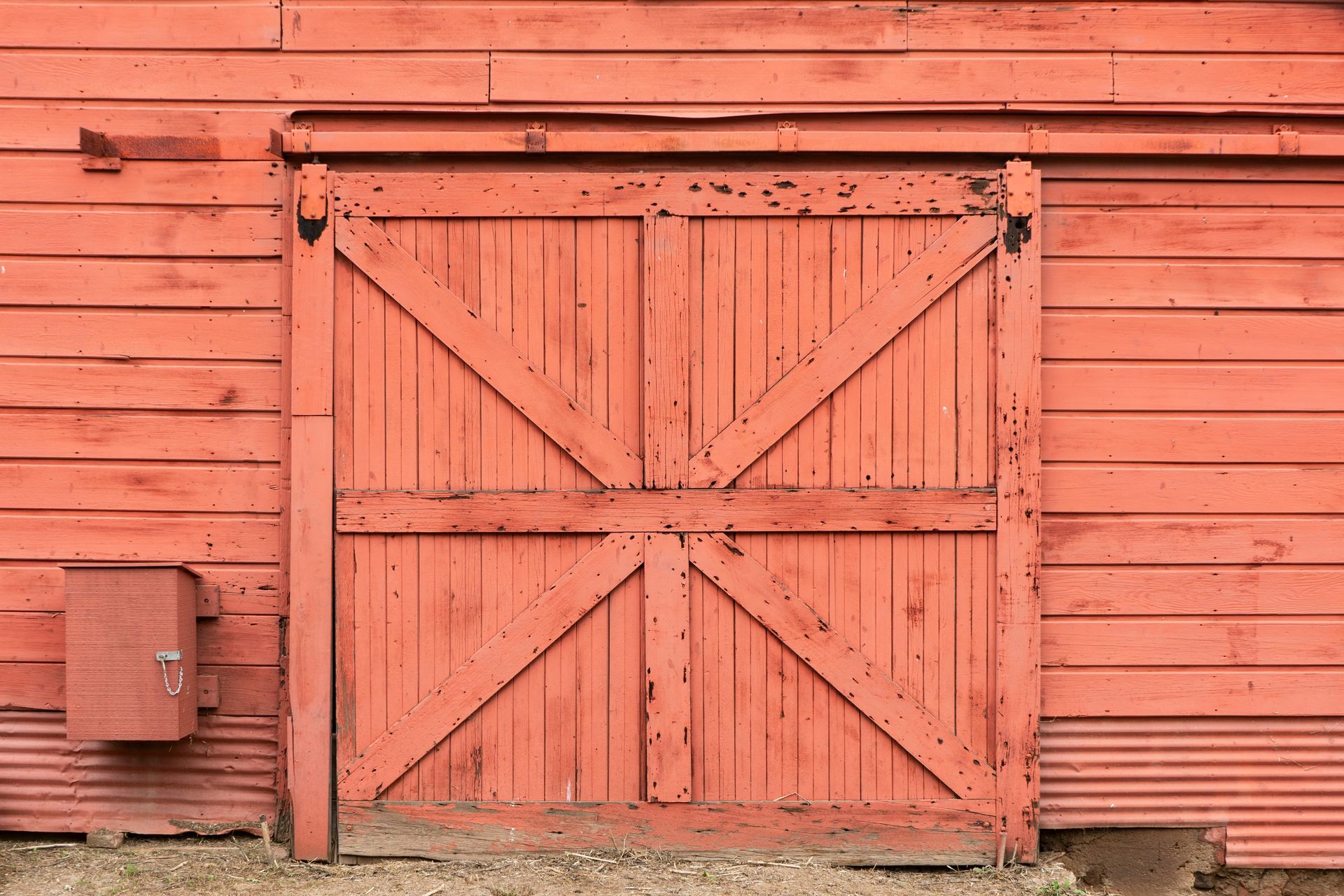 A close up of a red barn door on a red barn.