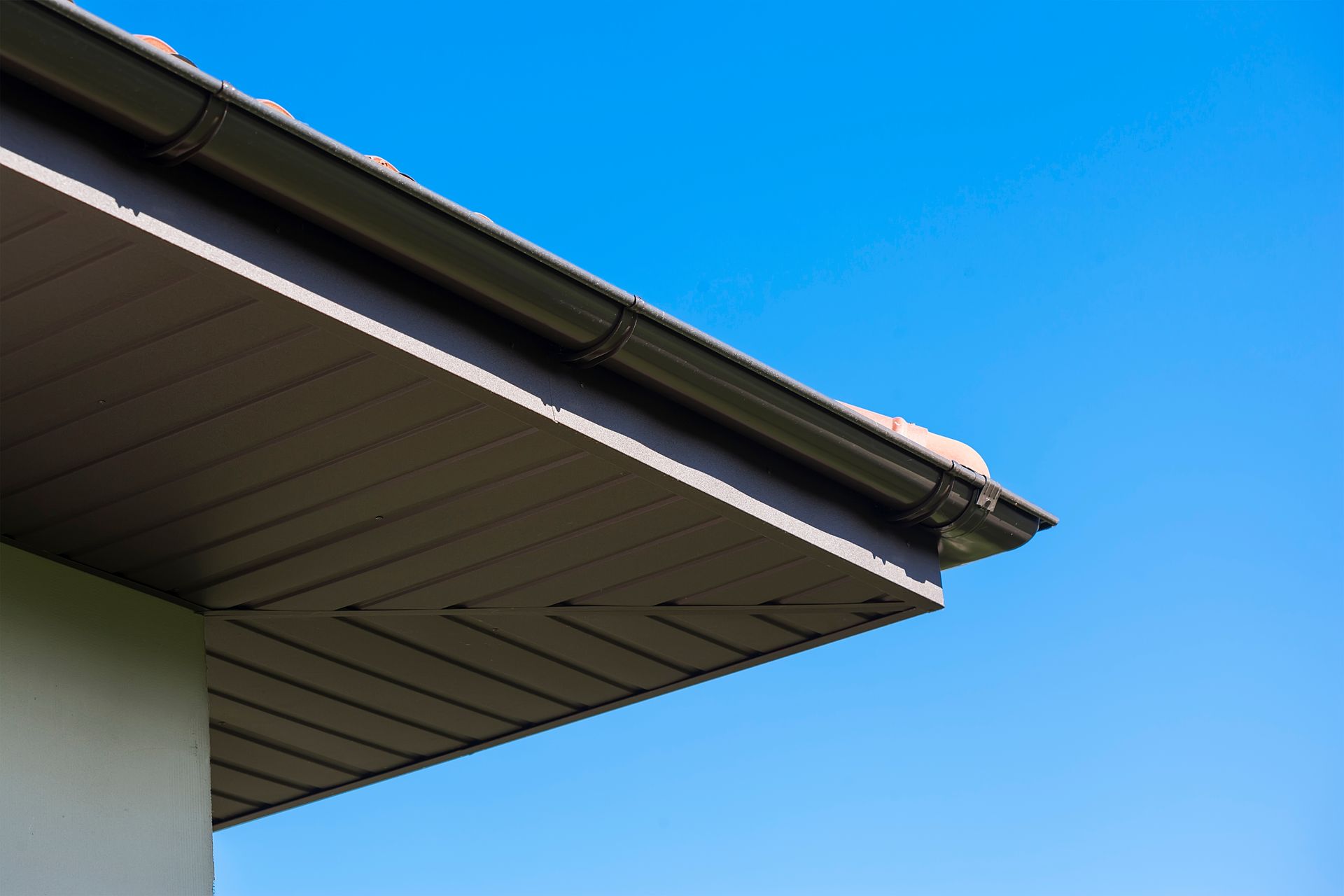 A close up of the roof of a house with a blue sky in the background.