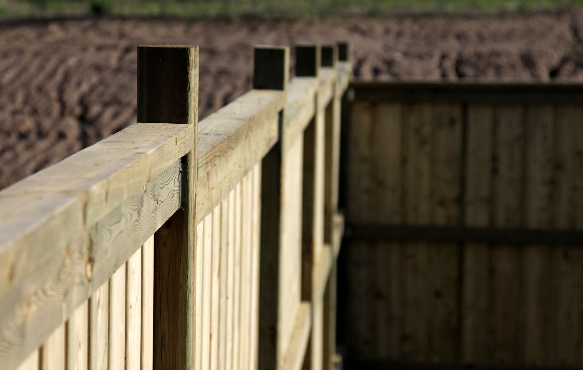 A close up of a wooden fence with a field in the background.