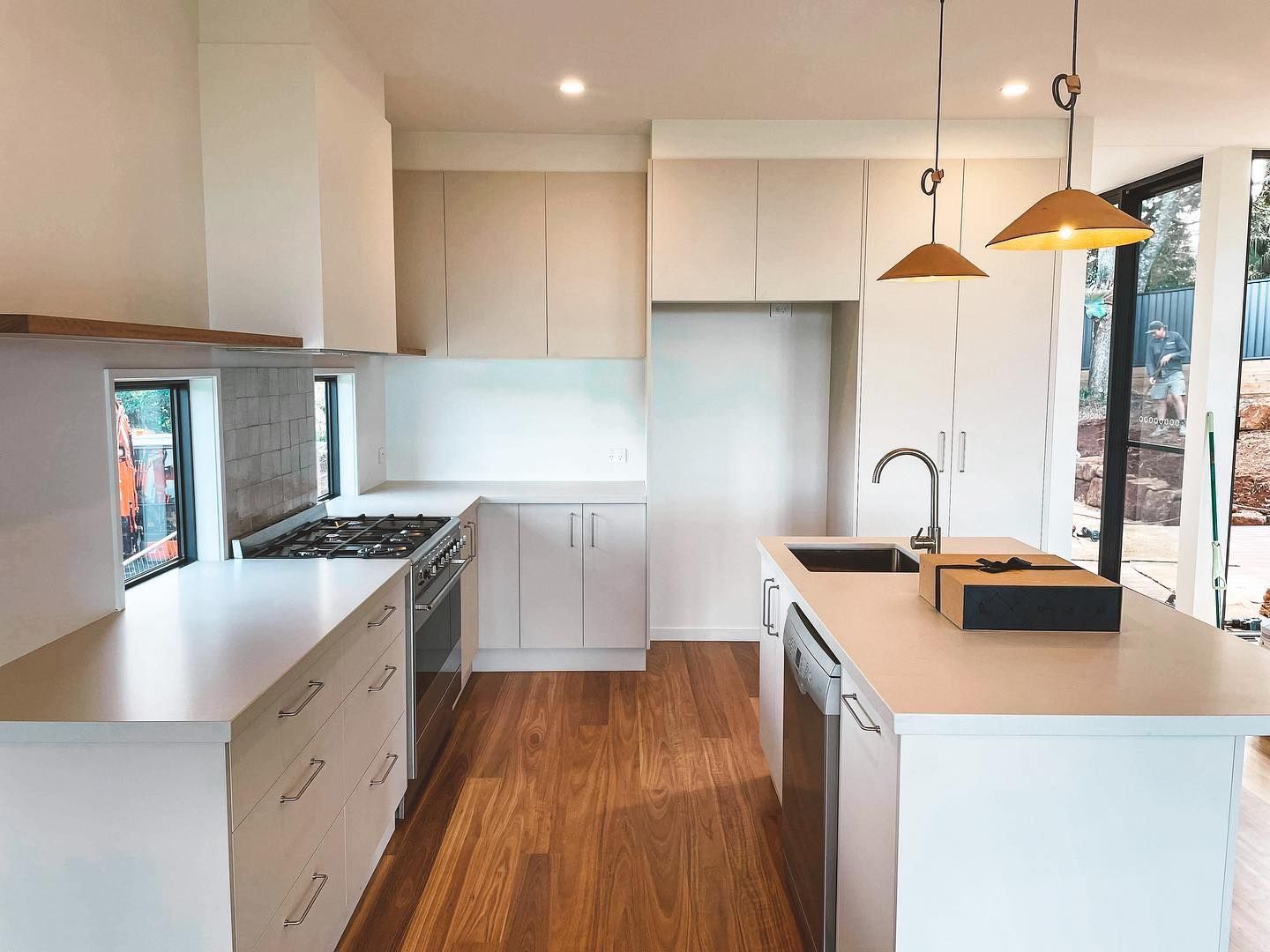 a kitchen with white cabinets , wooden floors , stainless steel appliances and a large island .