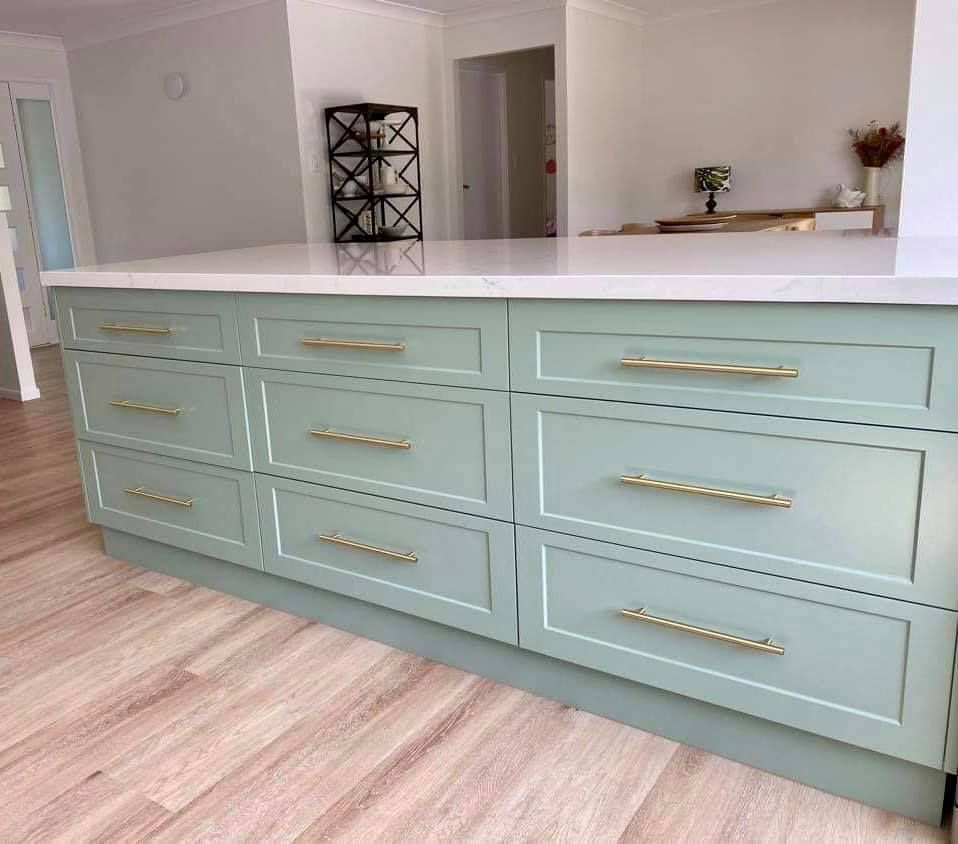 A kitchen with green cabinets and a white counter top.