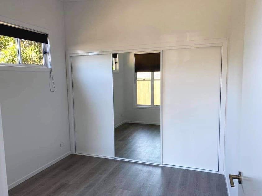 A bedroom with sliding glass doors and a mirror.
