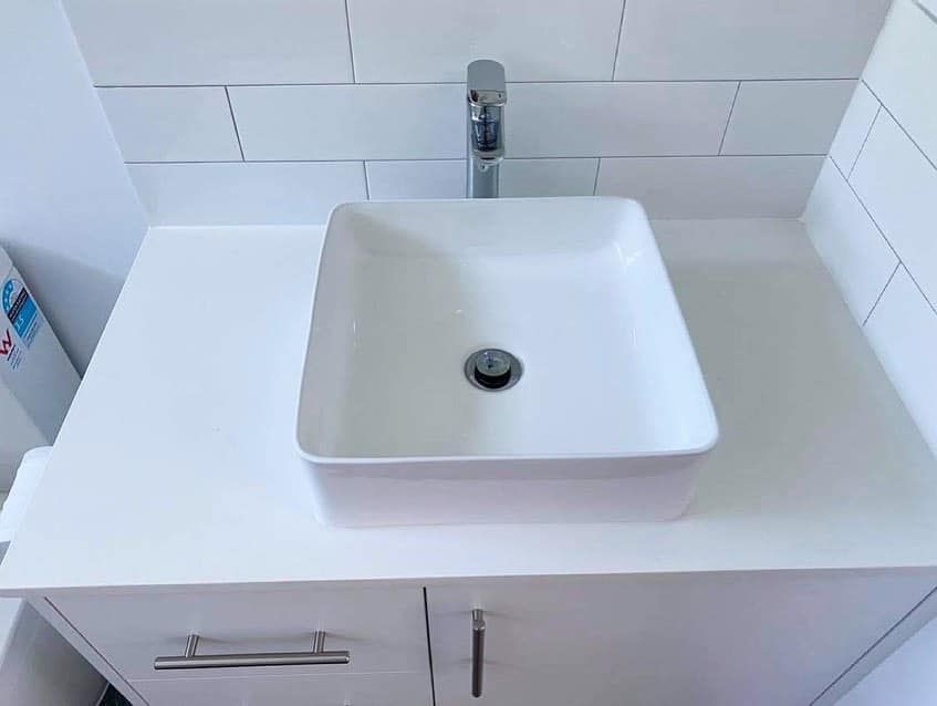 A bathroom sink is sitting on top of a white counter.