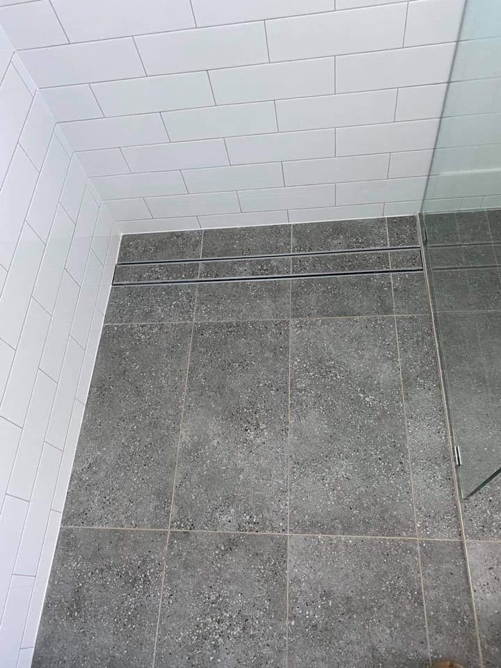 A bathroom with a tiled floor and white brick walls.