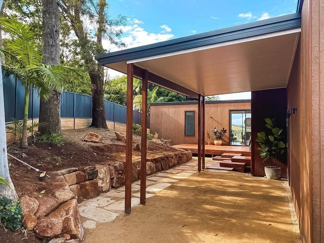 a wooden house with a covered driveway in front of it .