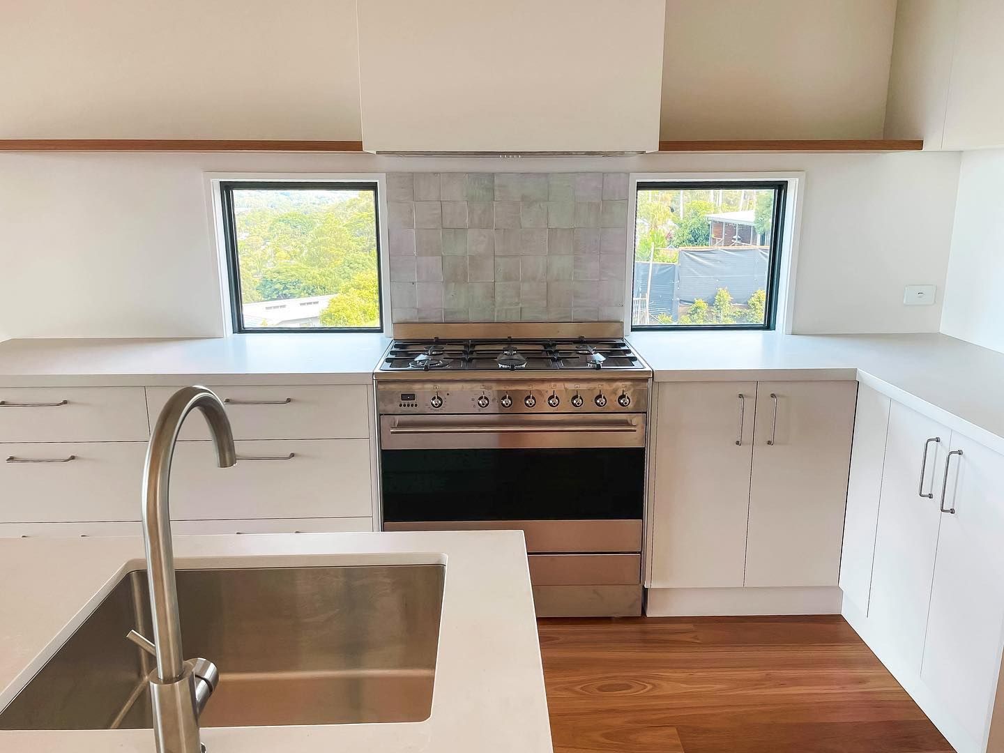 A kitchen with white cabinets , stainless steel appliances , a sink and a stove.