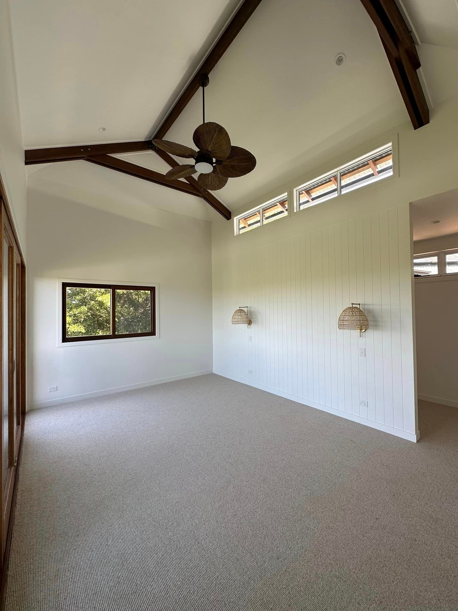 An empty room with a ceiling fan and a window.