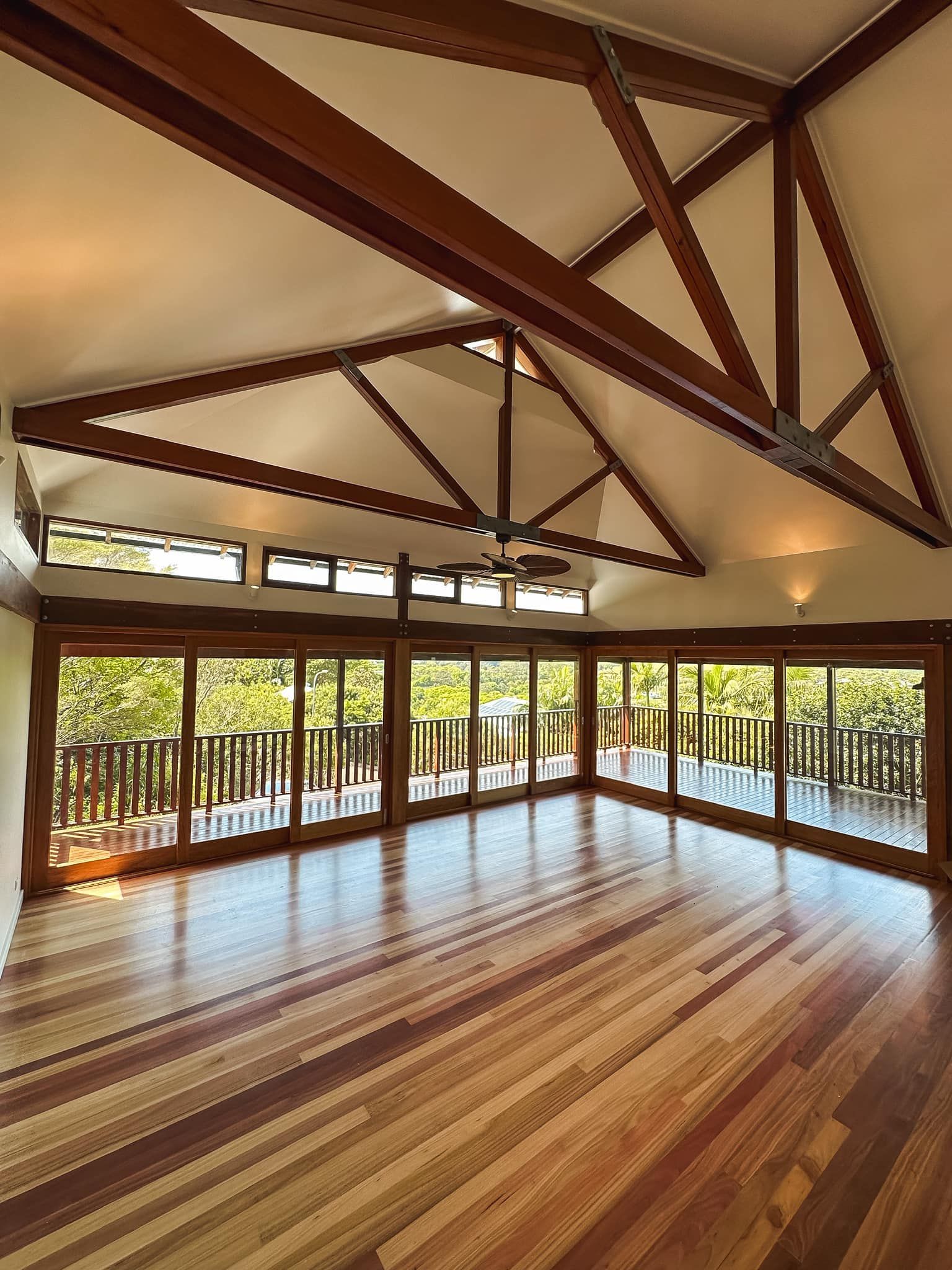 An empty room with lots of windows and wooden beams