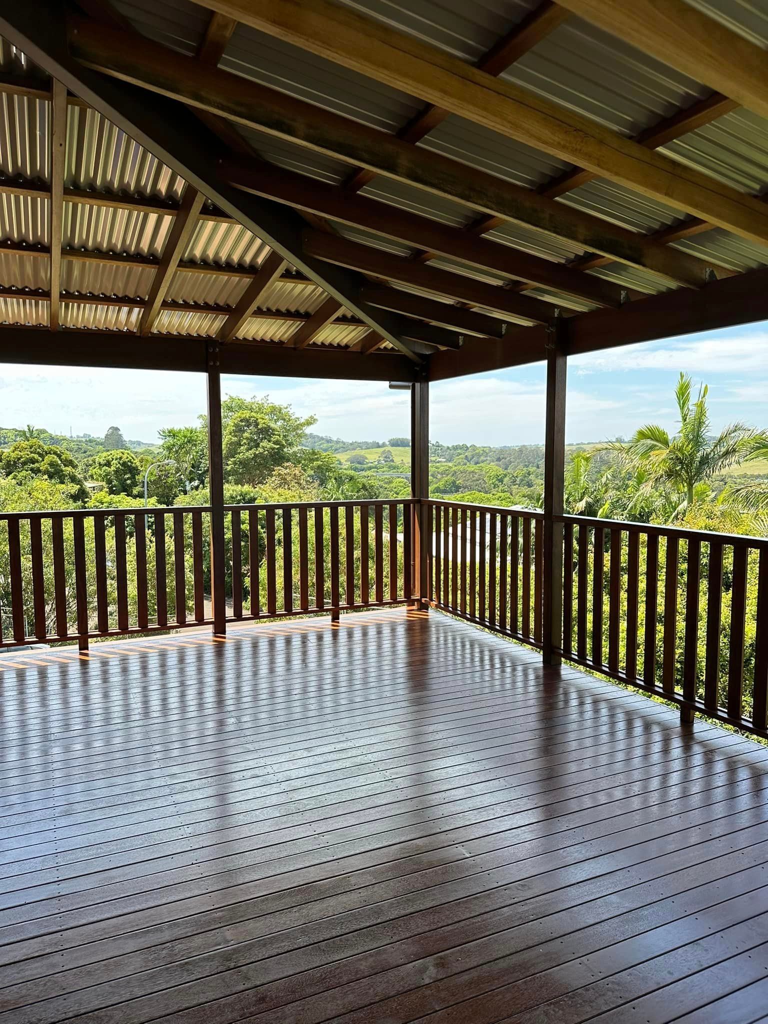 An empty deck with a wooden railing and a view of trees
