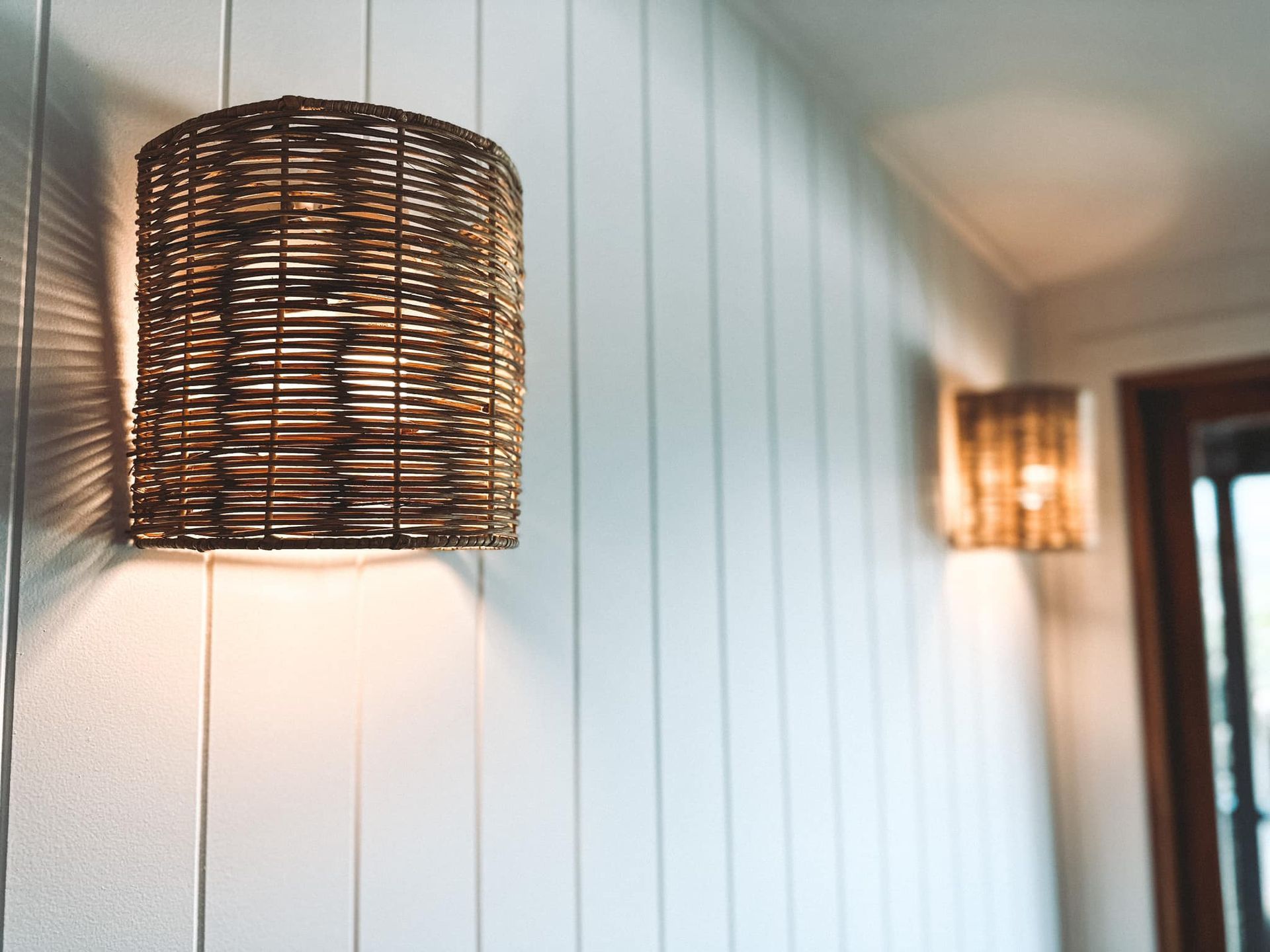 A wicker lamp hanging from a white wall