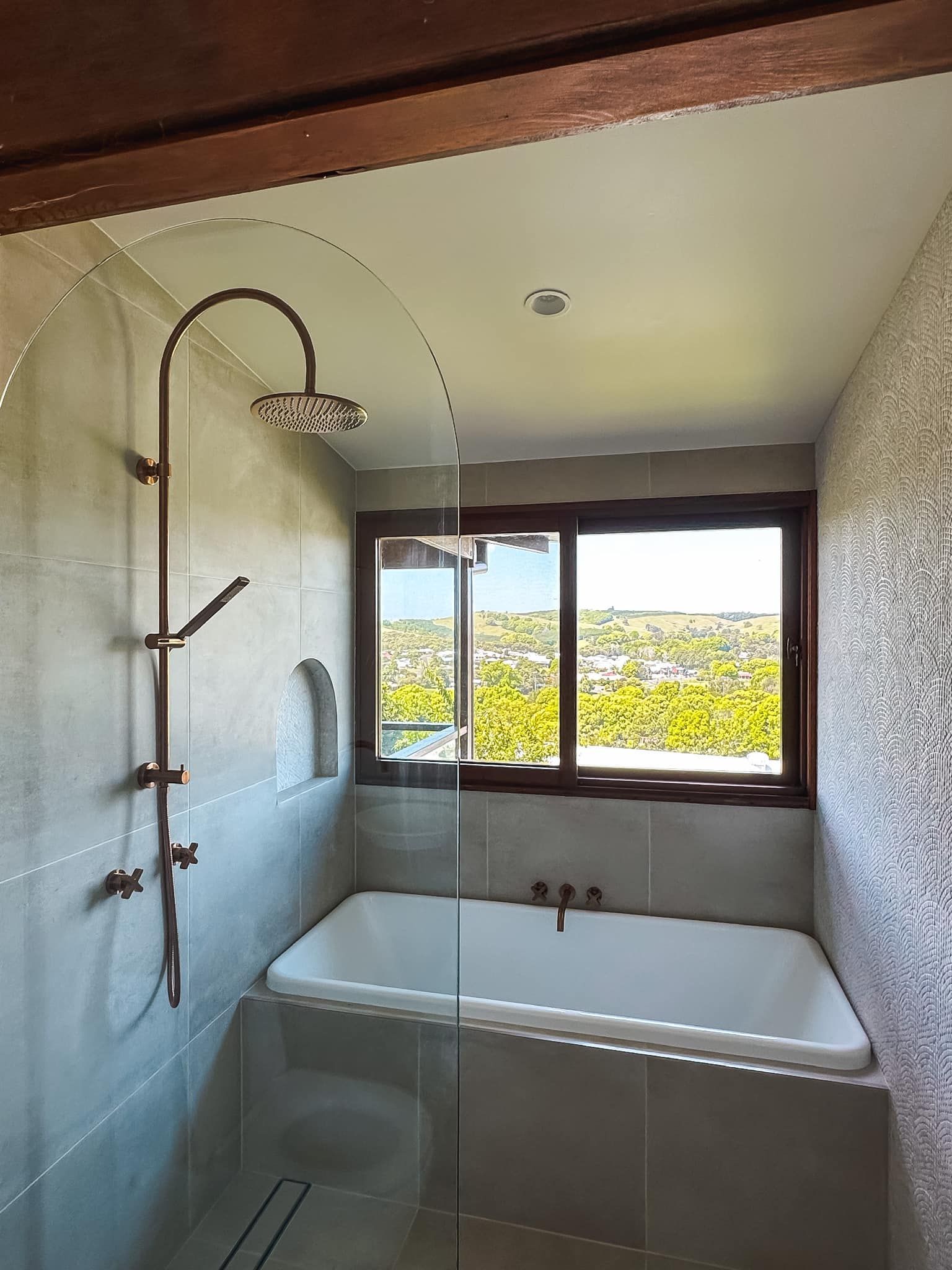 A bathroom with a bathtub , shower , and window.