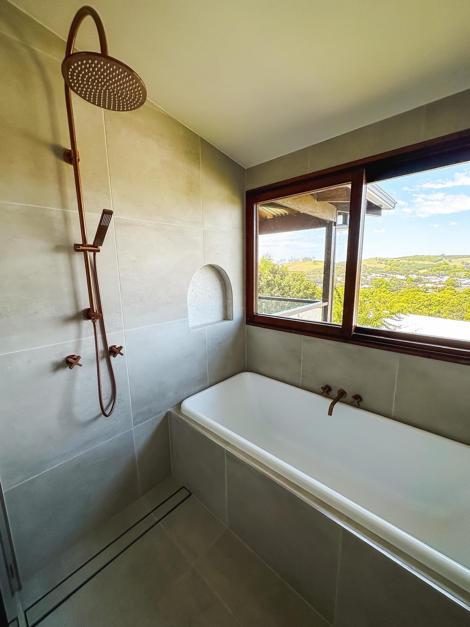 A bathroom with a bathtub , shower , and window.