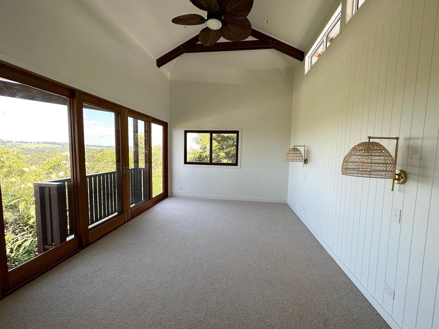 An empty room with a ceiling fan and lots of windows