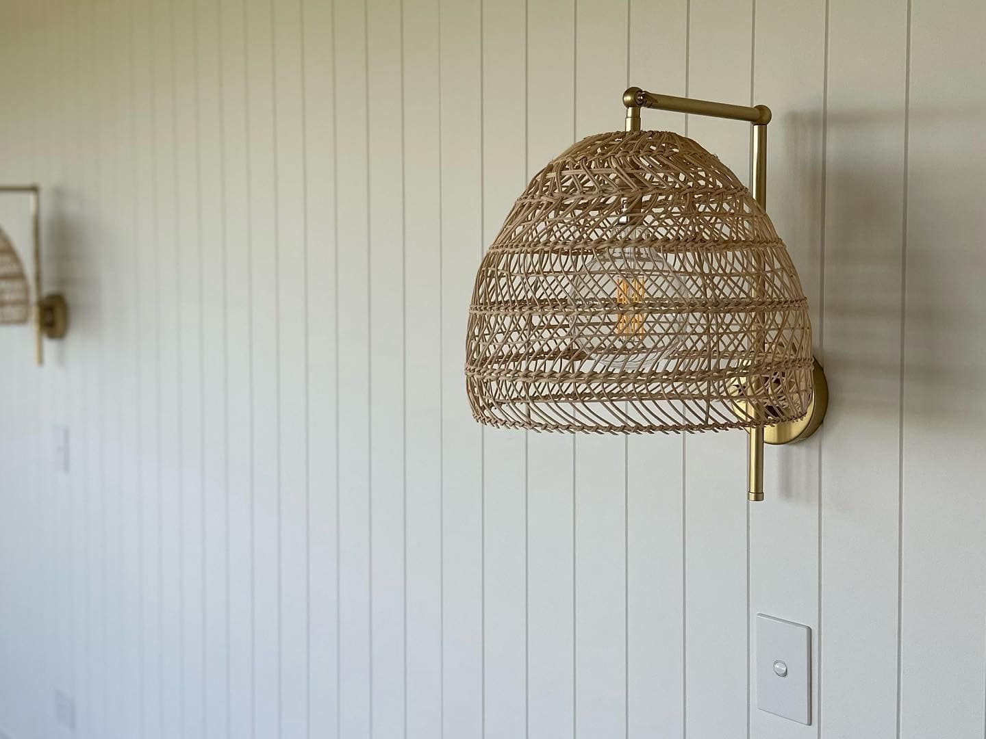 A wicker lamp is hanging on a white wall.