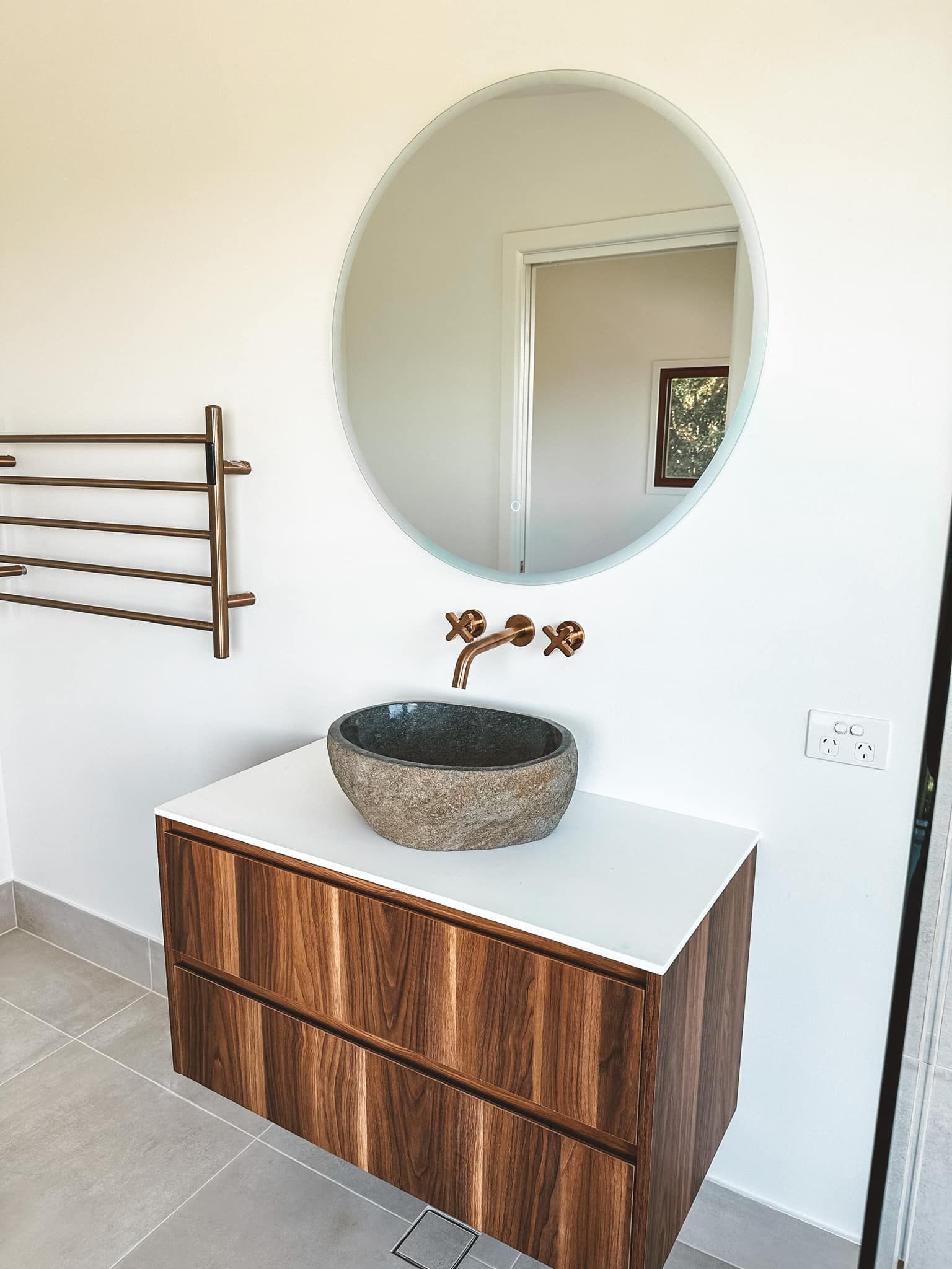 A bathroom with a sink , mirror and towel rack.