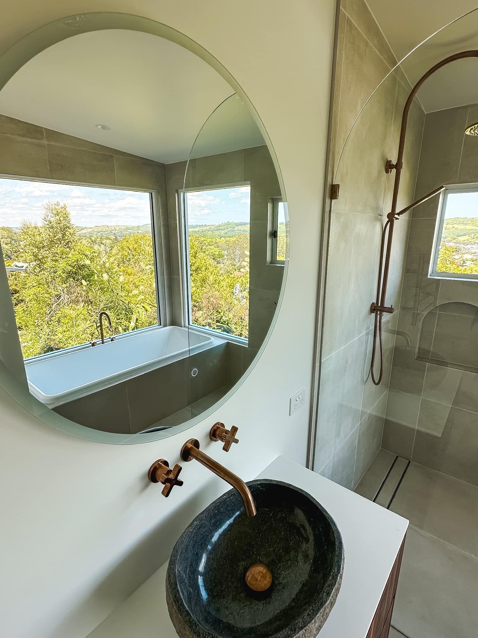 A bathroom with a sink and a round mirror