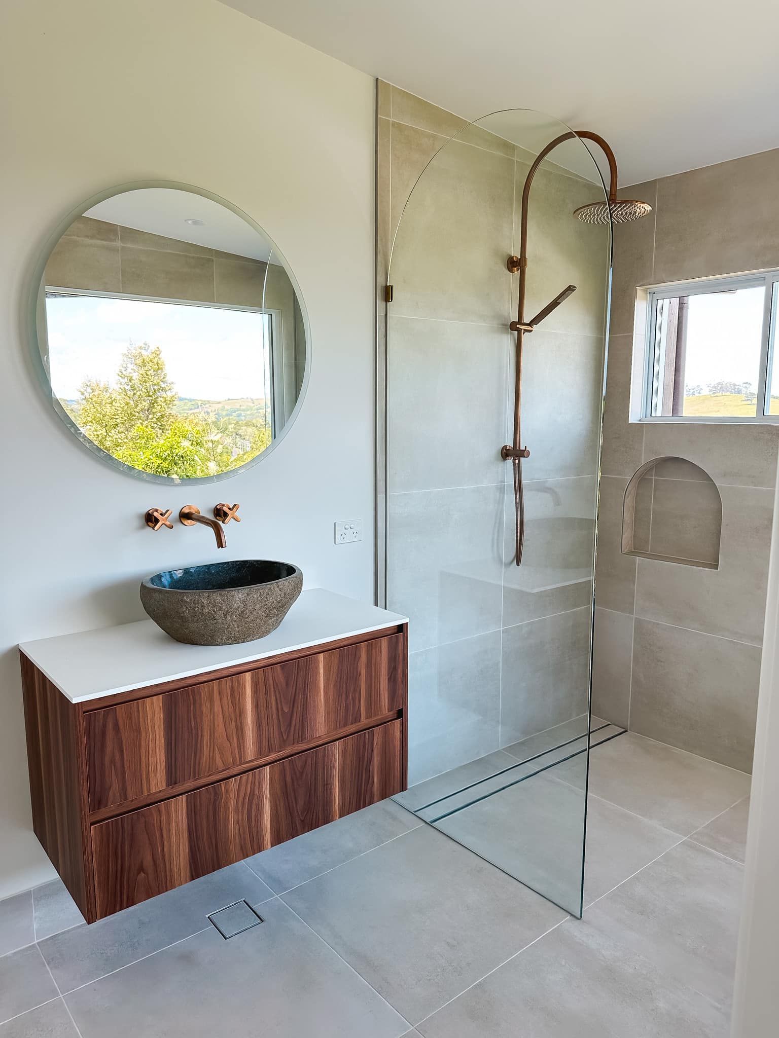 A bathroom with a sink , mirror and walk in shower.