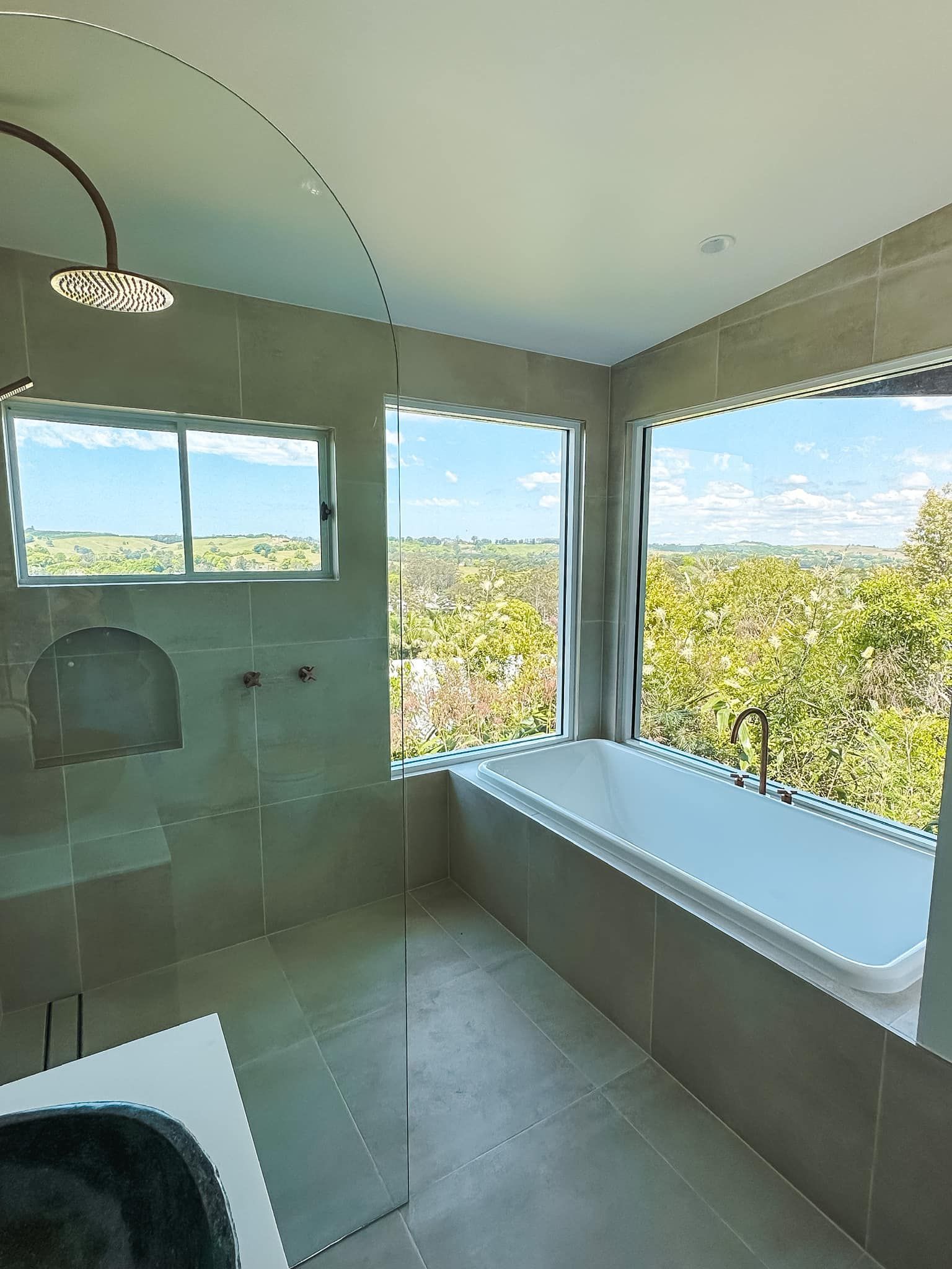 A bathroom with a bathtub , shower , sink and window.