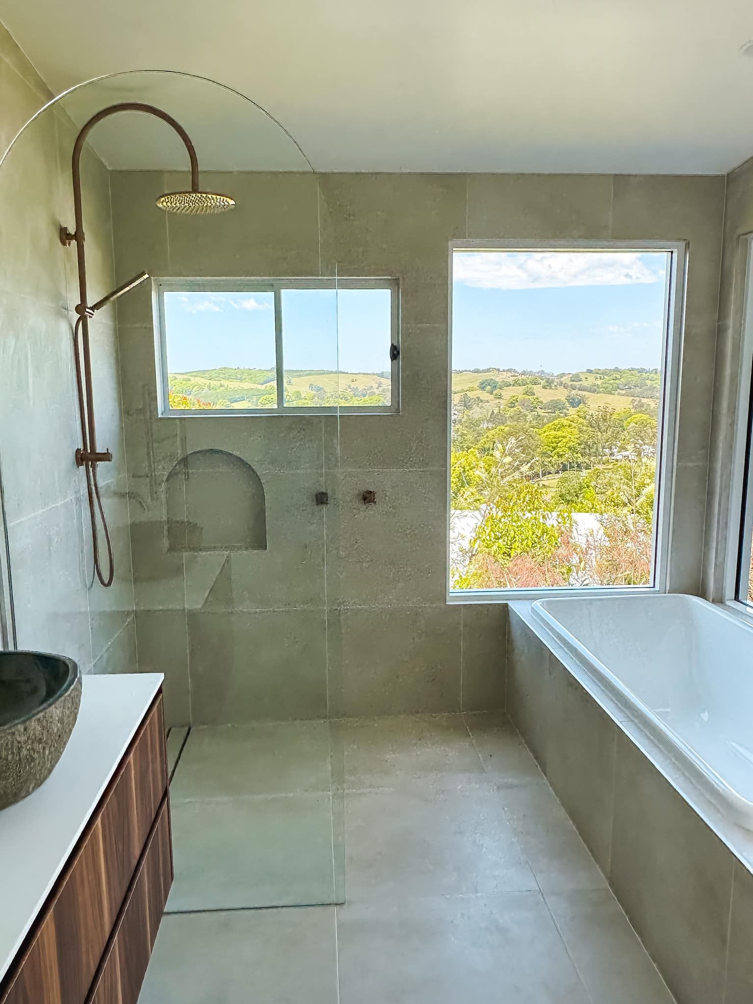 a bathroom with a bathtub , sink , shower and window .