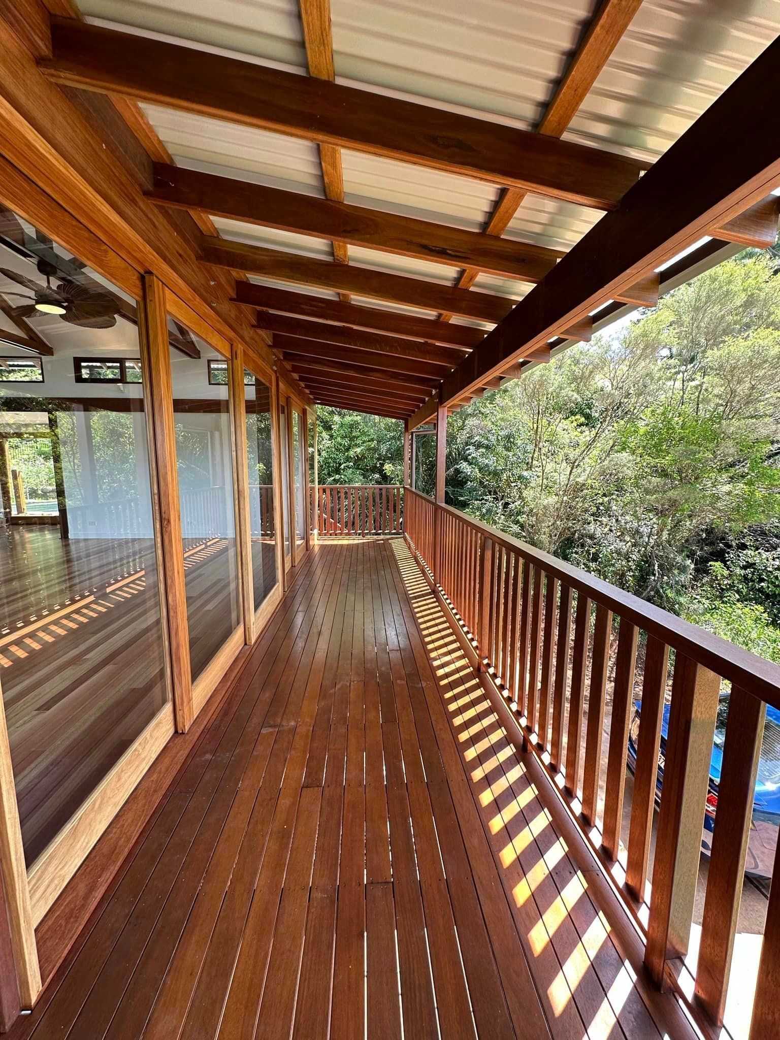 A long wooden deck with a railing and lots of windows.