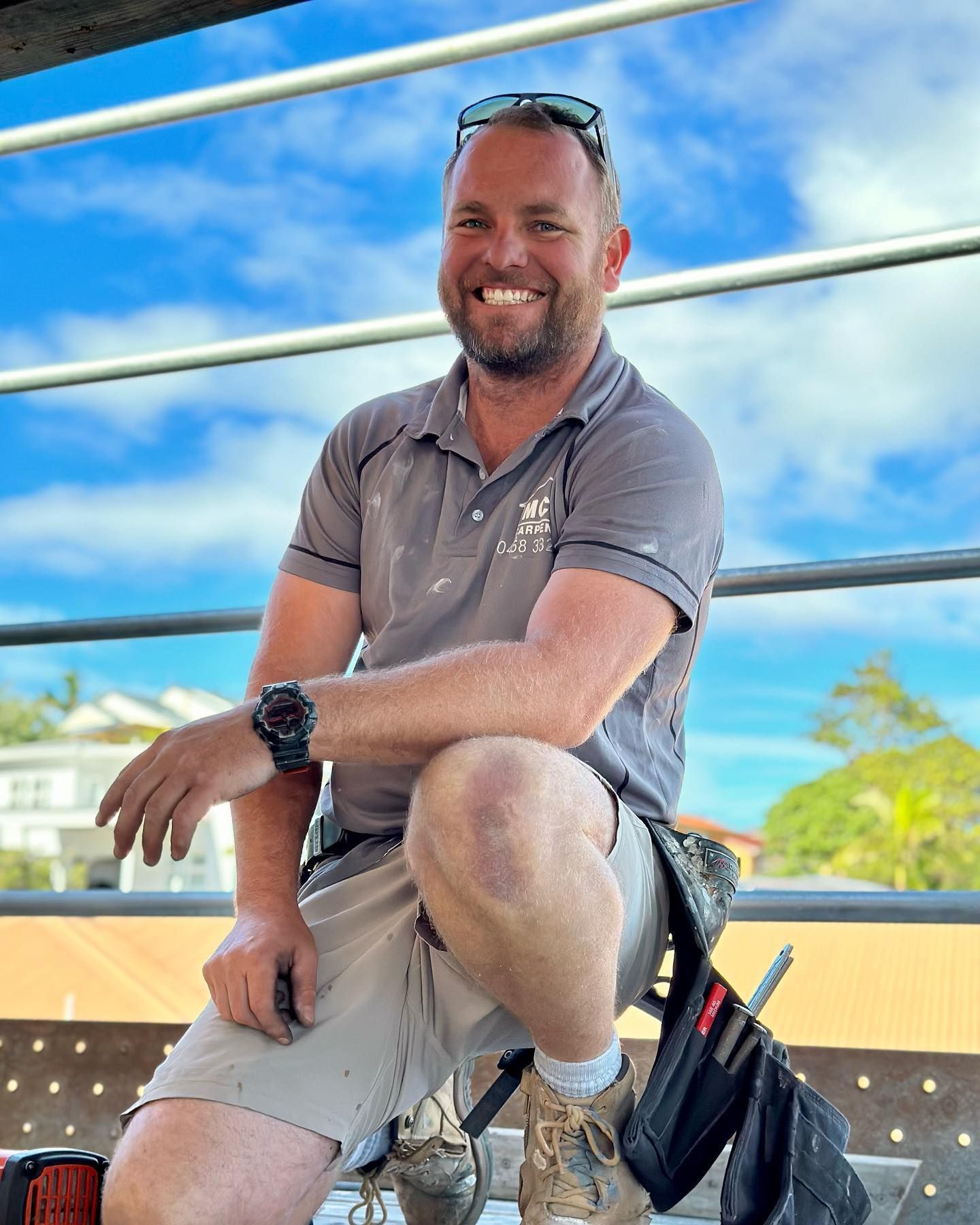 a man is sitting on a railing with his legs crossed and smiling .