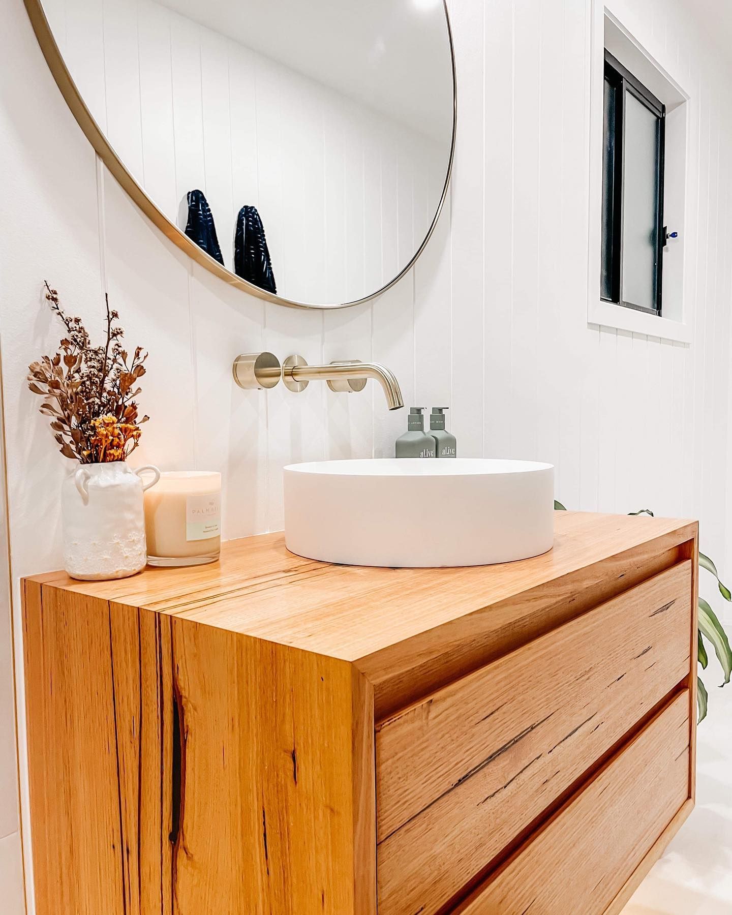 a bathroom with a wooden vanity , sink , mirror and window .