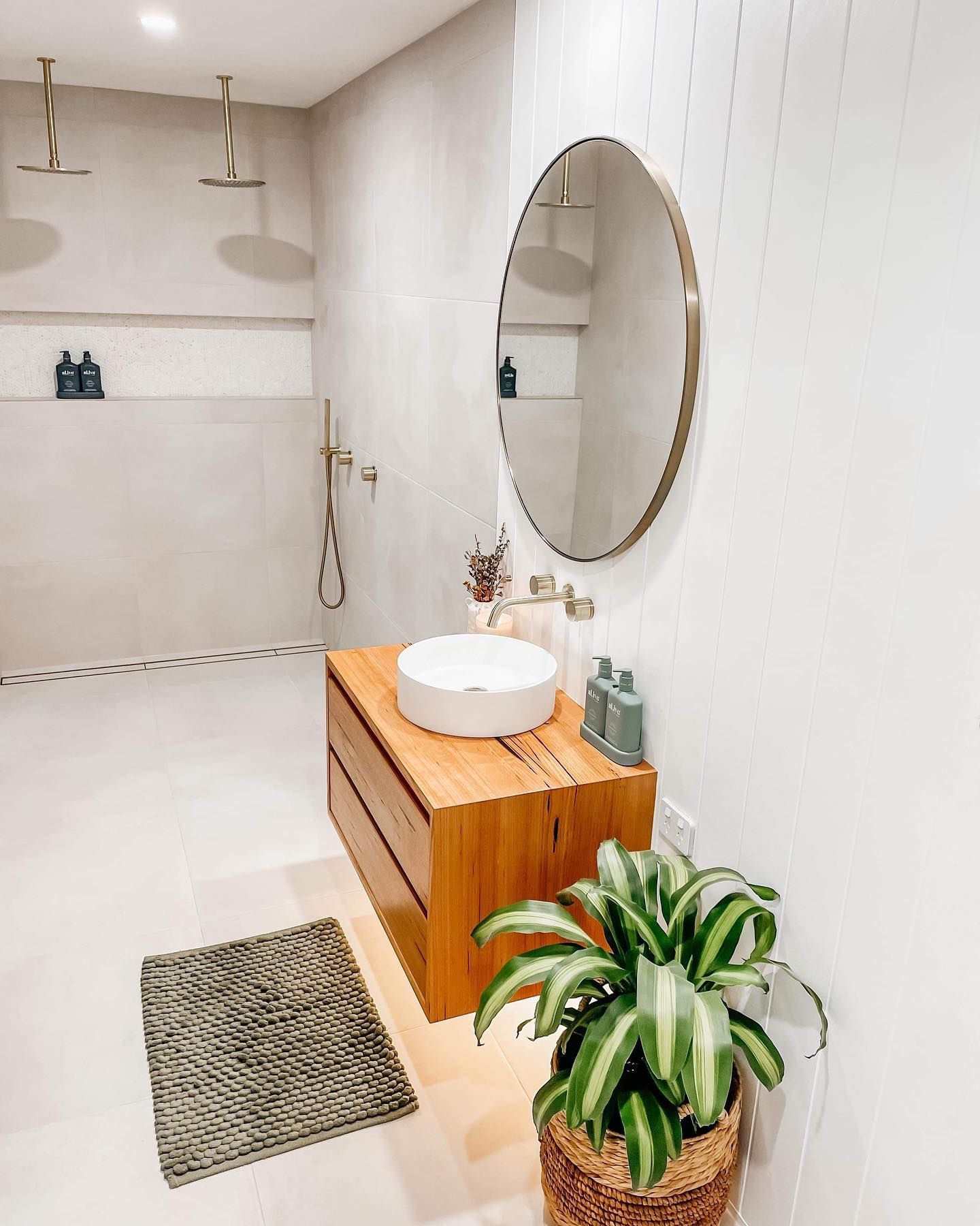 A bathroom with a sink , mirror , and plant.