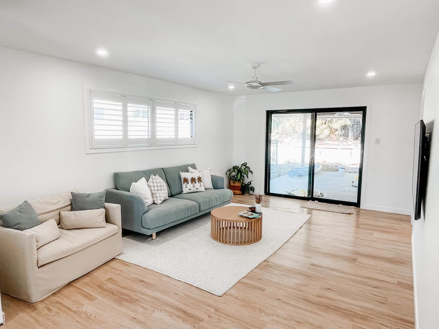 A living room with a couch , chair , coffee table and sliding glass doors.