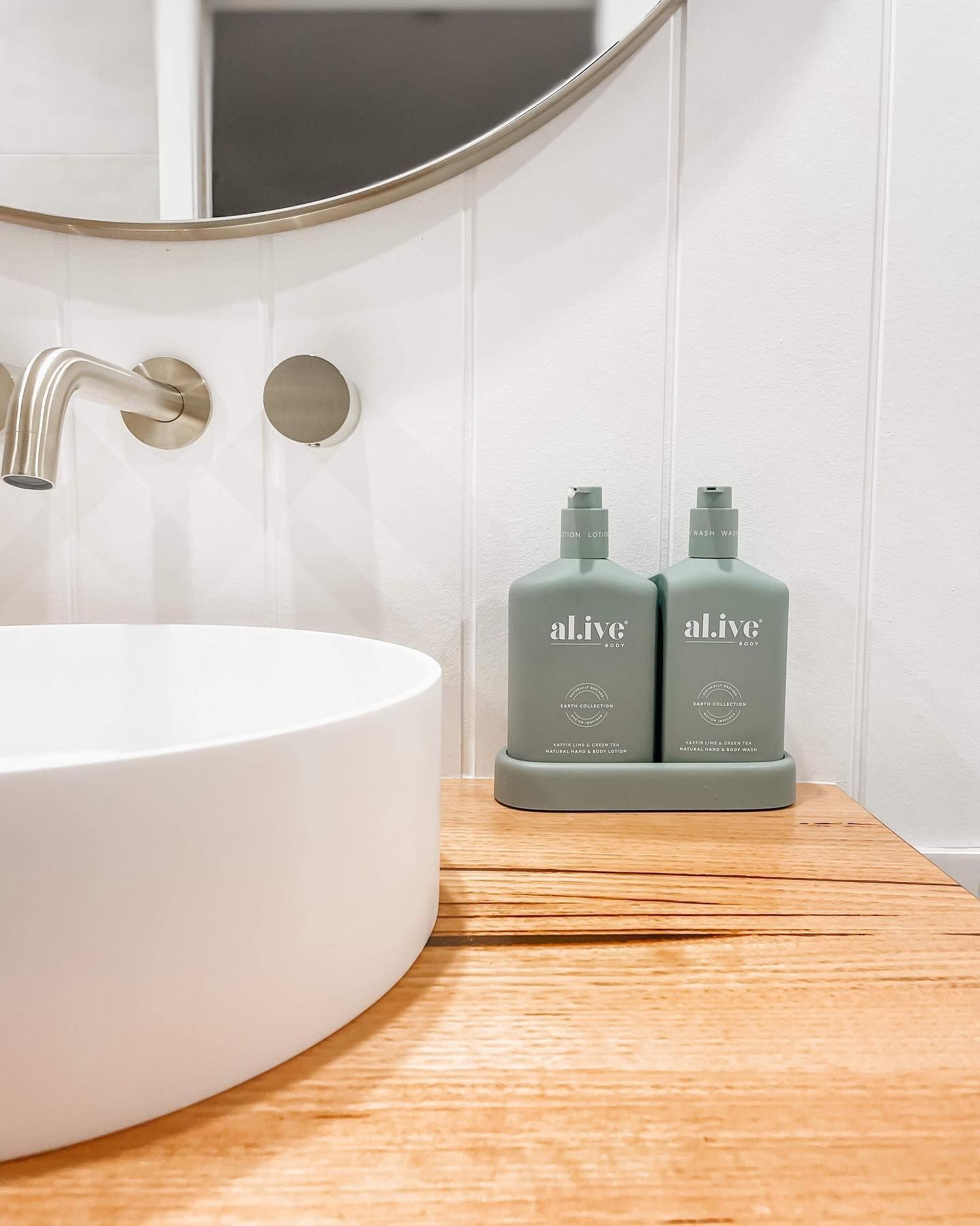 A bathroom sink with two bottles of lotion on a wooden counter.