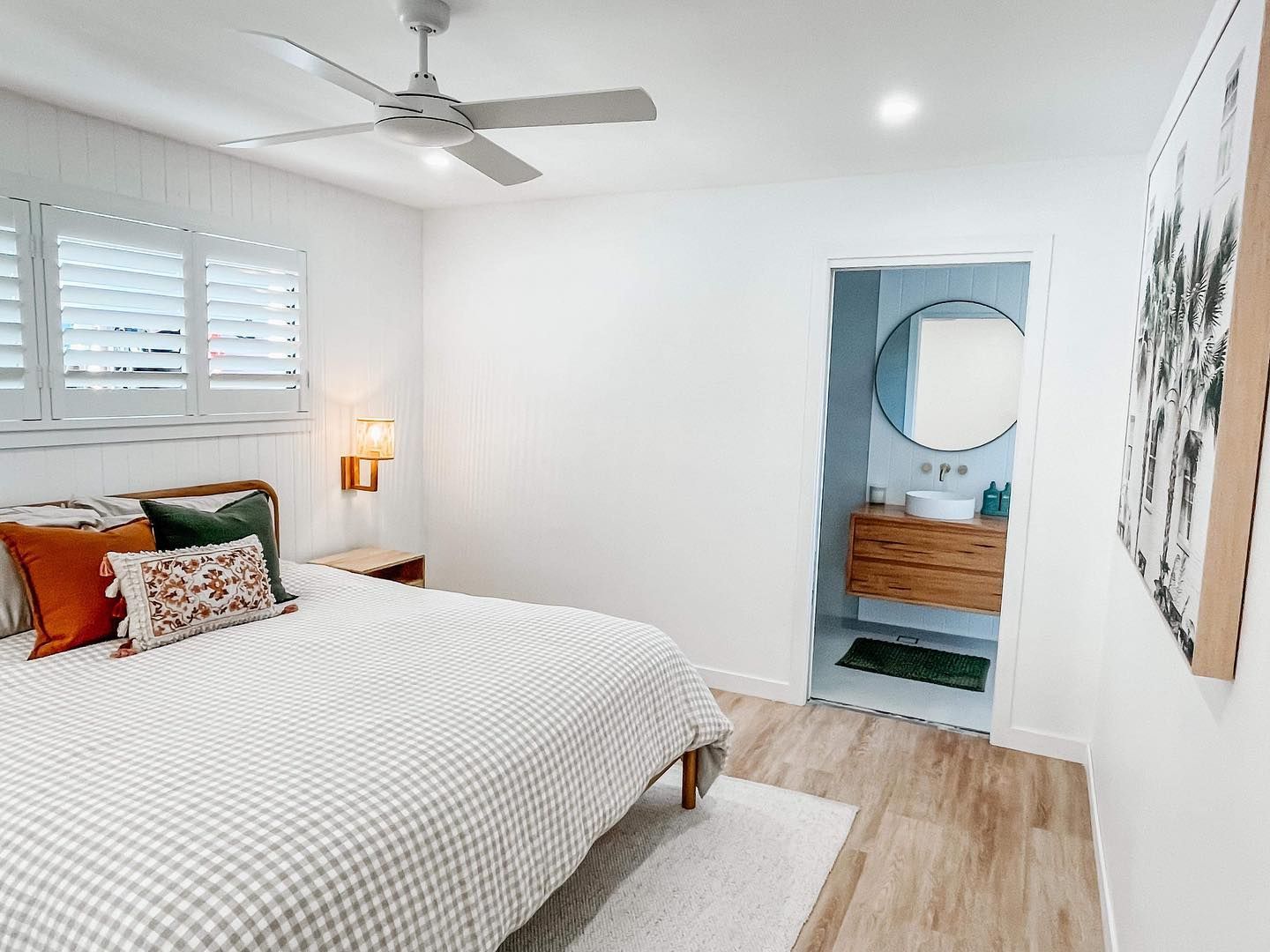 A bedroom with a bed , ceiling fan , and bathroom.