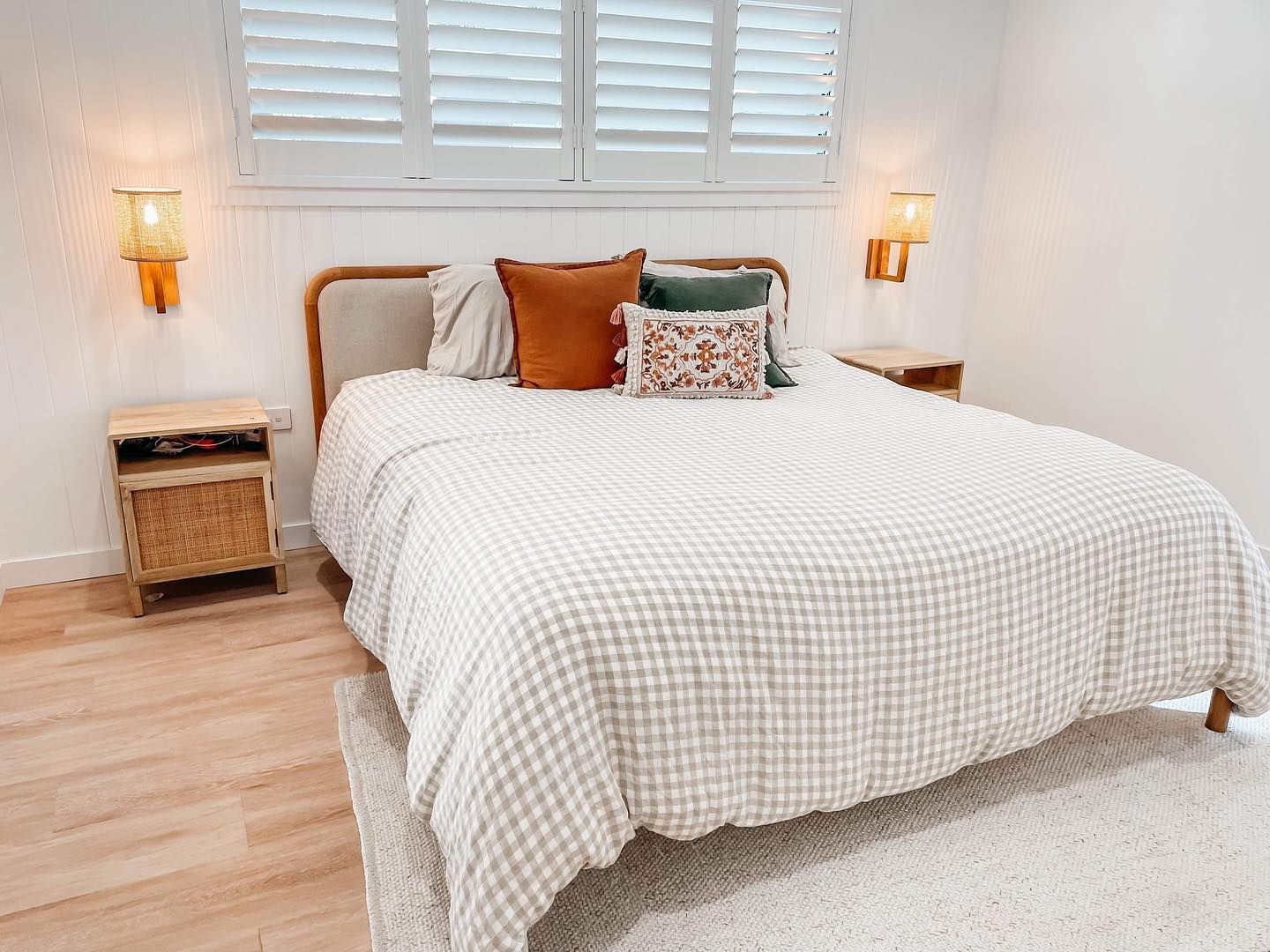 a bedroom with a bed , nightstands , and shutters on the windows .