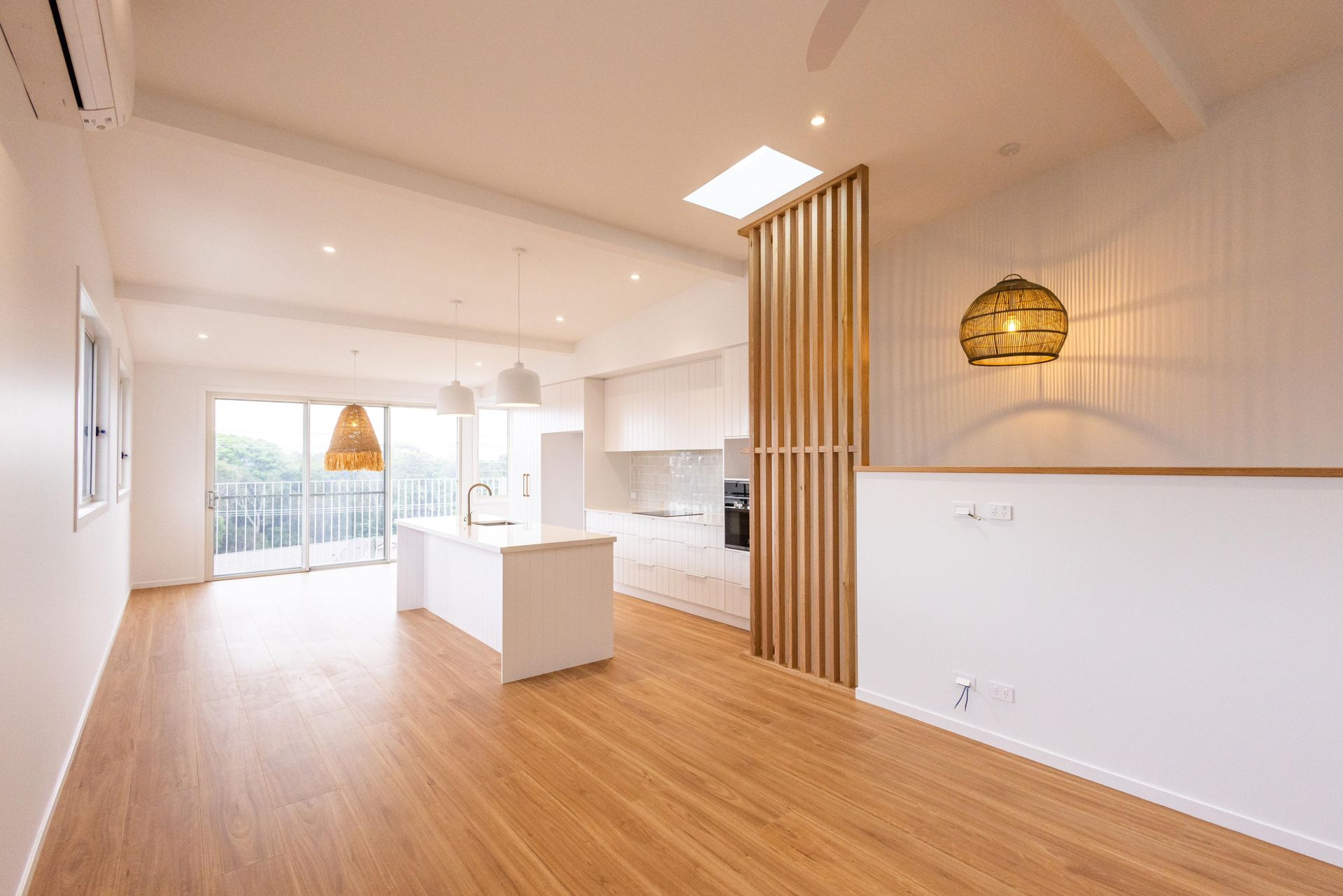 An empty living room with hardwood floors and a kitchen.