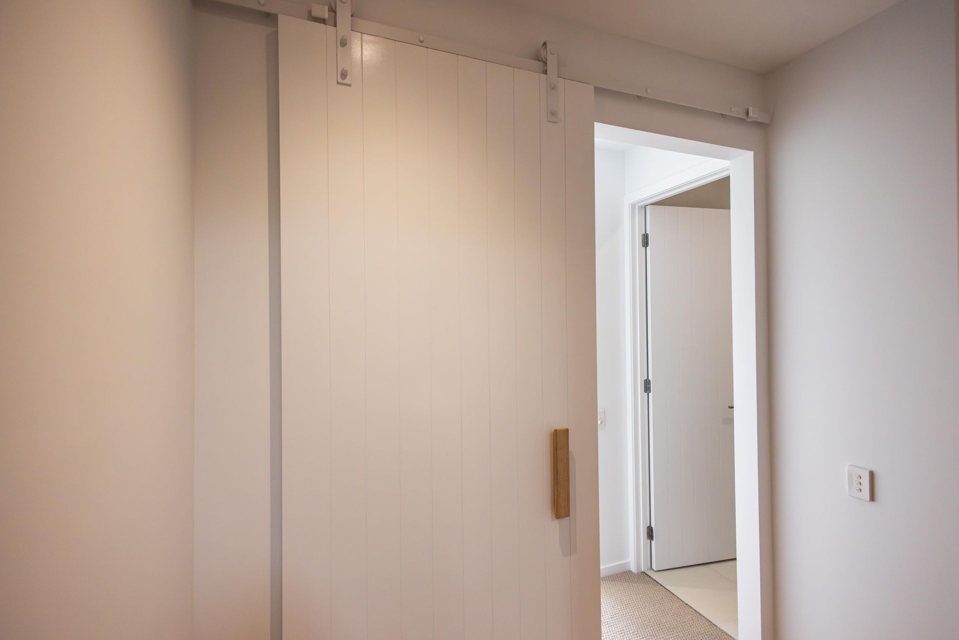 A white sliding barn door is open to a hallway.