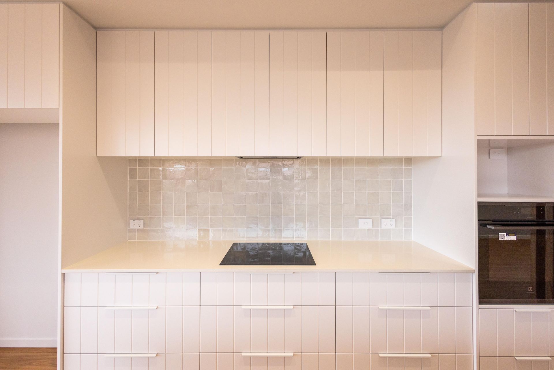 A kitchen with white cabinets and a stove top oven.